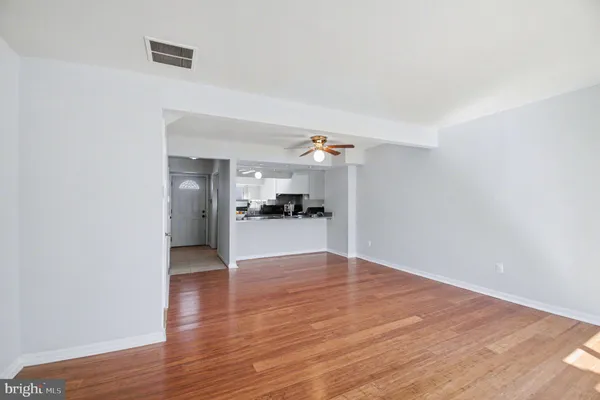 a view of a kitchen and an empty room with wooden floor