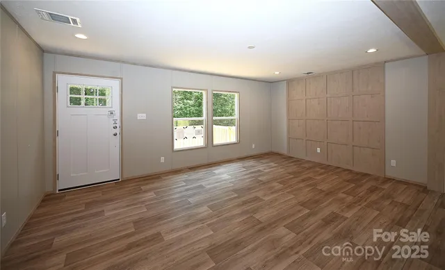 a large kitchen with kitchen island wooden floors wooden cabinets a sink and a window