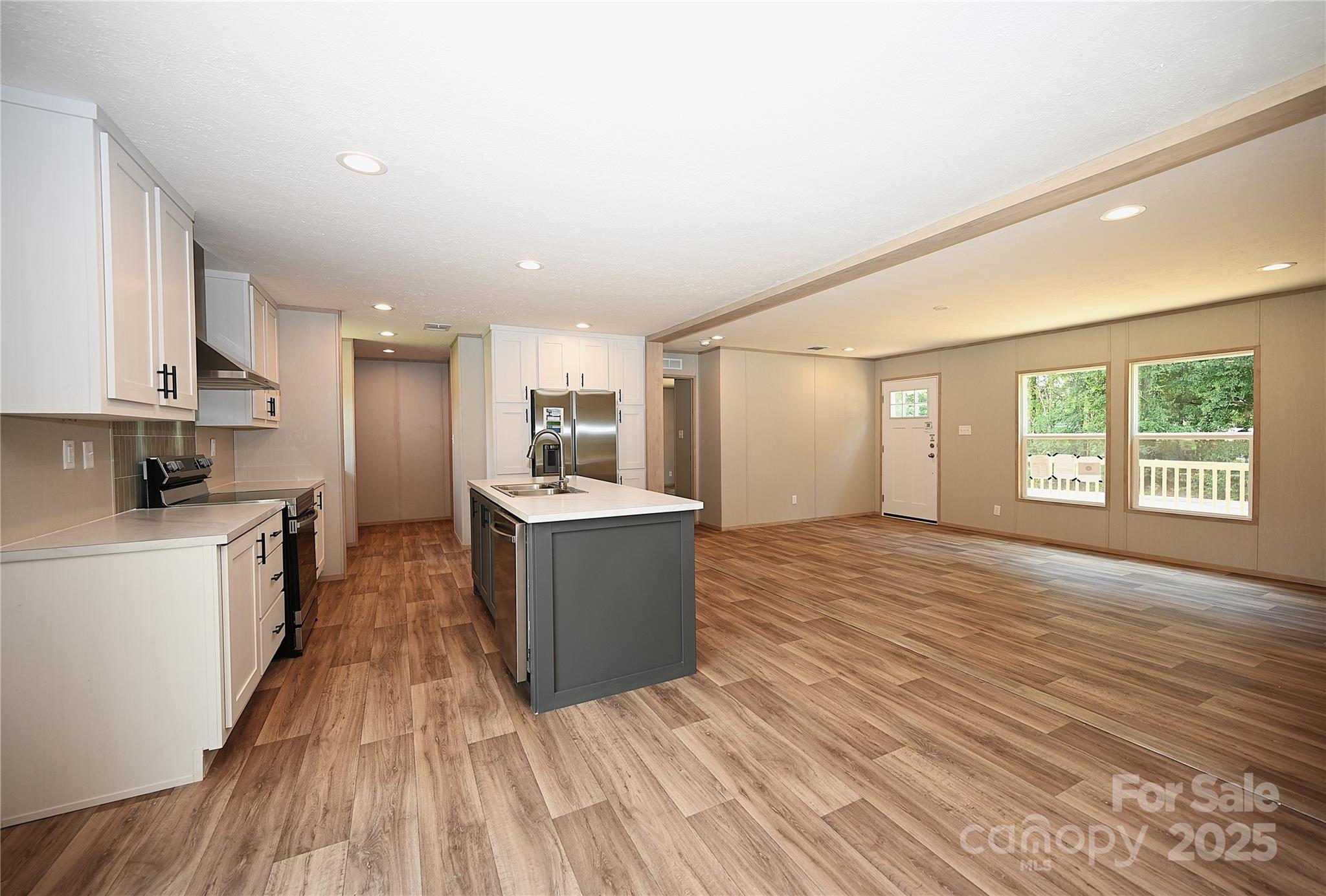1213 Renno Road Clinton, SC 29325 - Photo 4 of 17 a large kitchen with kitchen island wooden floors wooden cabinets a sink and a window