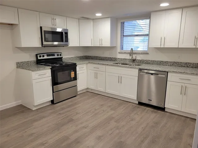 a kitchen with granite countertop a sink and steel appliances