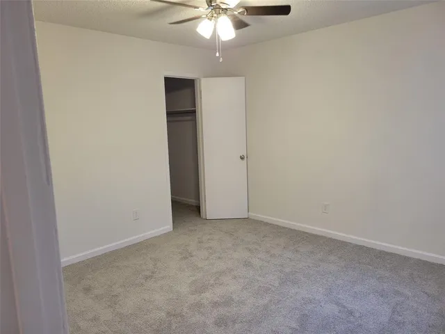 an empty room with a chandelier fan and closet area