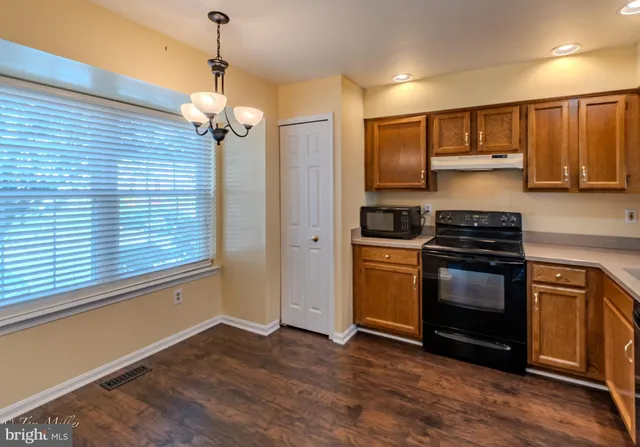 a kitchen with stainless steel appliances granite countertop a refrigerator a sink dishwasher a stove and white cabinets with wooden floor