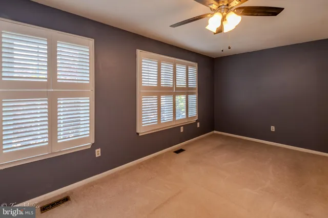 a view of an empty room with chandelier fan