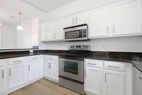 a kitchen with granite countertop white cabinets stainless steel appliances and sink
