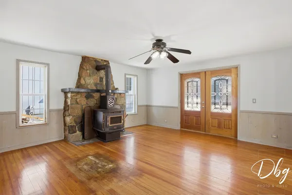 a view of an empty room with wooden floor and a ceiling fan