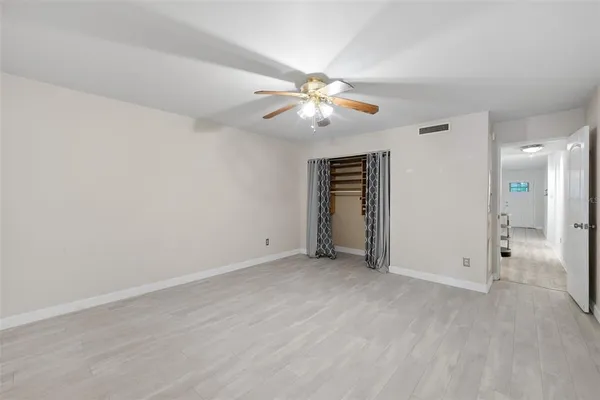 an empty room with closet and a ceiling fan
