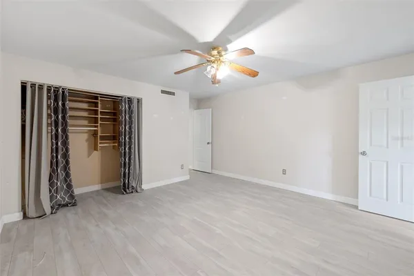 an empty room with closet and a ceiling fan