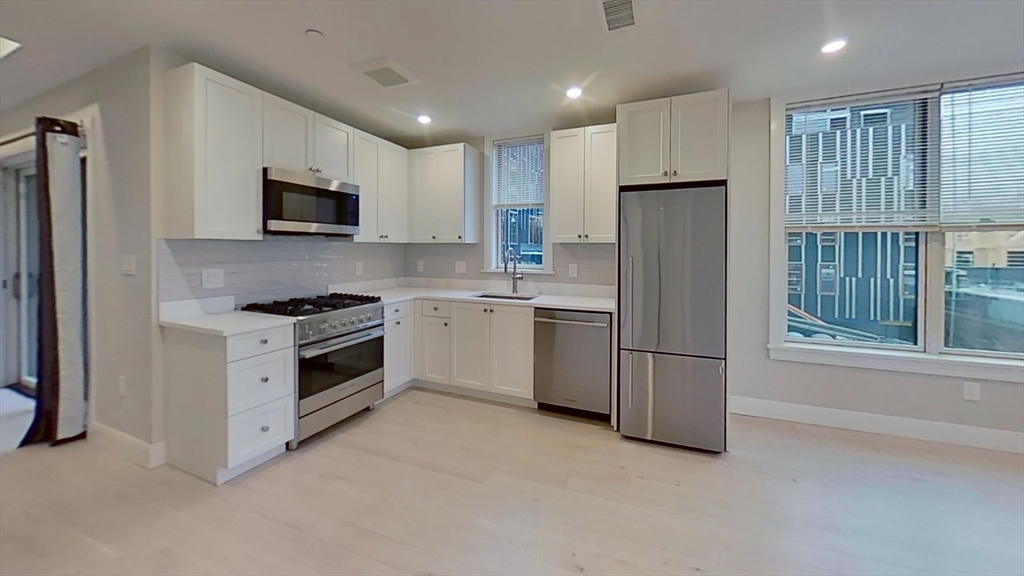 197 Green Street, Unit 305 Boston, MA 02130 - Photo 2 of 7 a kitchen with stainless steel appliances a refrigerator stove and microwave