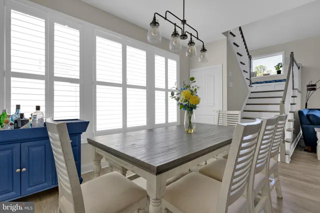 a very nice looking kitchen with a dining table chairs wooden floors and a large window