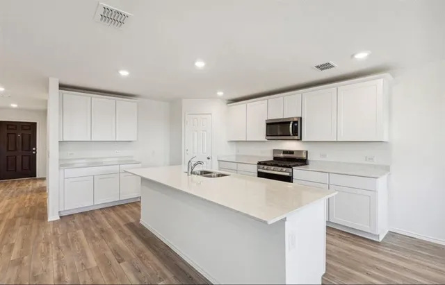 a kitchen with a sink a microwave a stove and cabinets