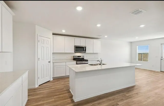 a kitchen with stainless steel appliances a stove top oven a sink and a refrigerator