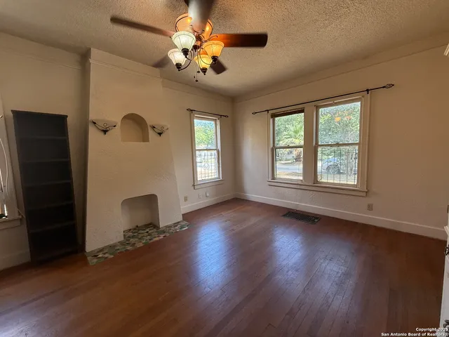 a view of an empty room with a window and wooden floor