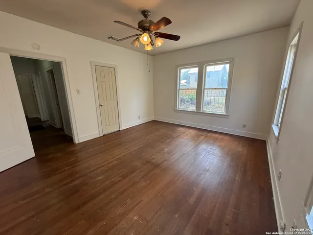 a view of an empty room with wooden floor and a window