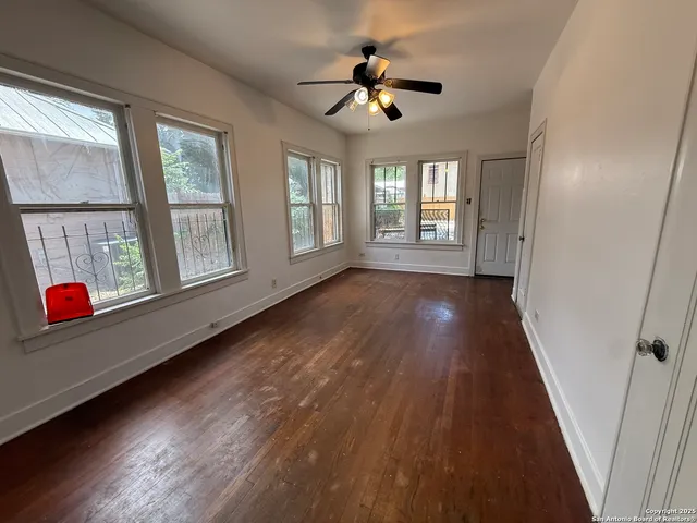 a view of an empty room with wooden floor and a window