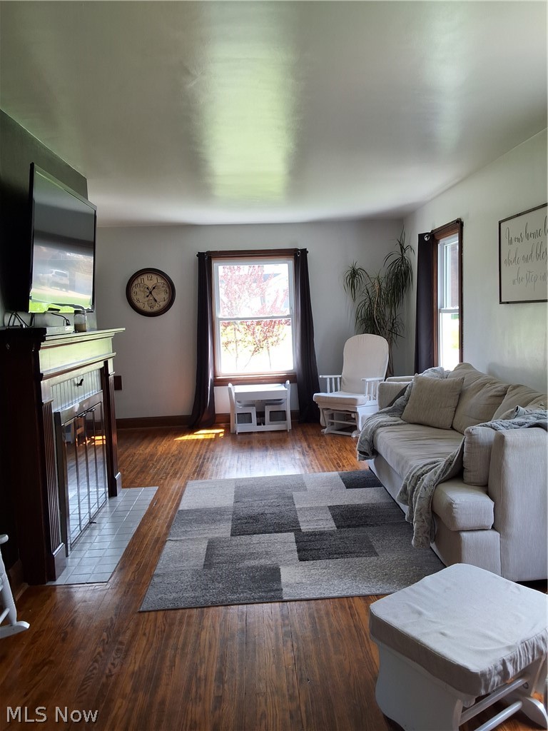 236 Bowland Road Mansfield, OH 44907 - Photo 10 of 34 Living area featuring wood-finish flooring, a dark wood fireplace surround with a light-tiled hearth, and multiple windows with dark trim