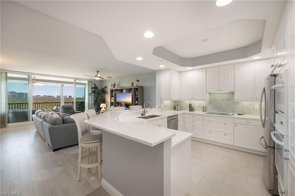 425 Cove Tower Drive, Unit 502 Naples, FL 34110 - Photo 7 of 18 a large white kitchen with a large window appliances and cabinets