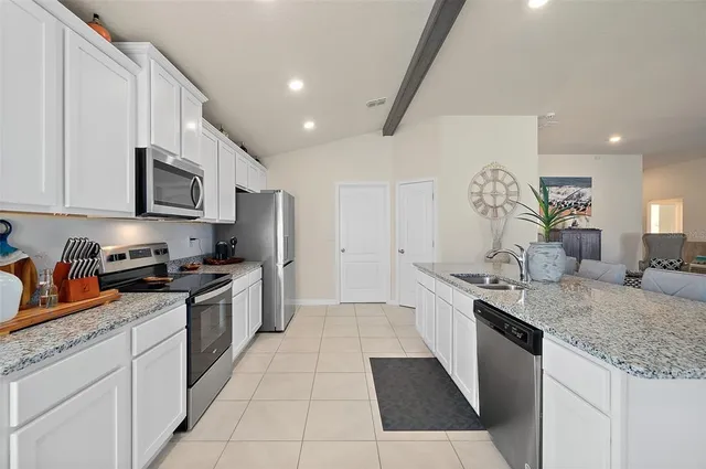 a large kitchen with stainless steel appliances granite countertop a stove sink and cabinets