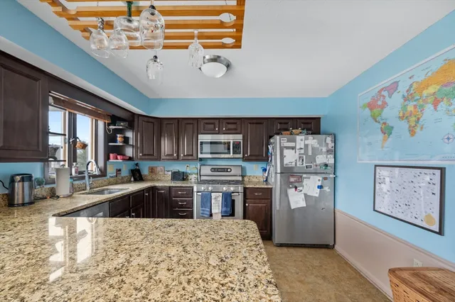 a kitchen with stainless steel appliances granite countertop a refrigerator a sink dishwasher a stove with wooden cabinets and floor