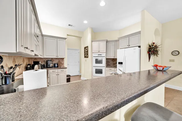 a kitchen with stainless steel appliances granite countertop a refrigerator a stove and white cabinets