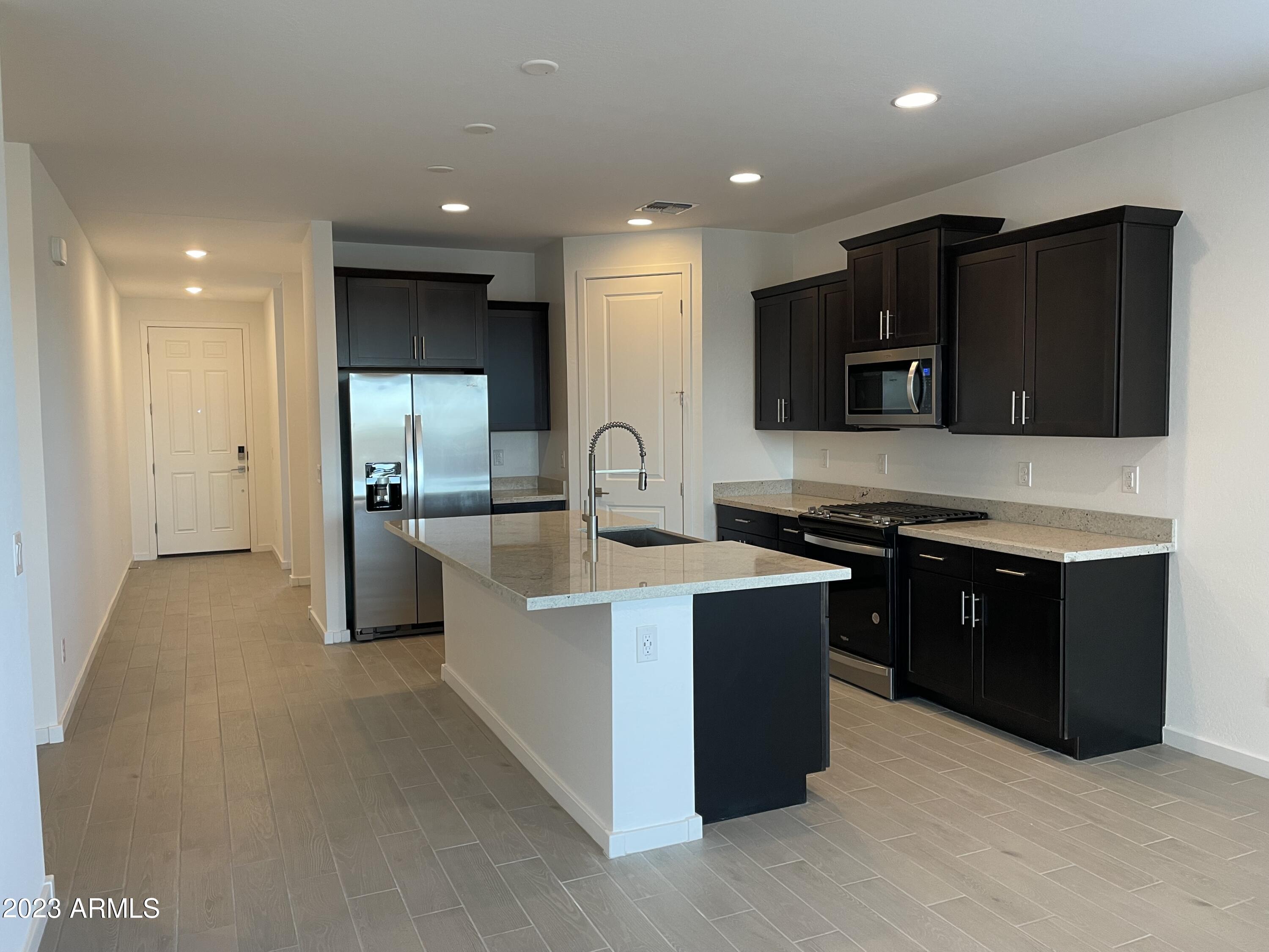 17401 West Red Fox Road Surprise, AZ 85387 - Photo 6 of 41 a large kitchen with stainless steel appliances kitchen island granite countertop a large counter top and a stove top oven