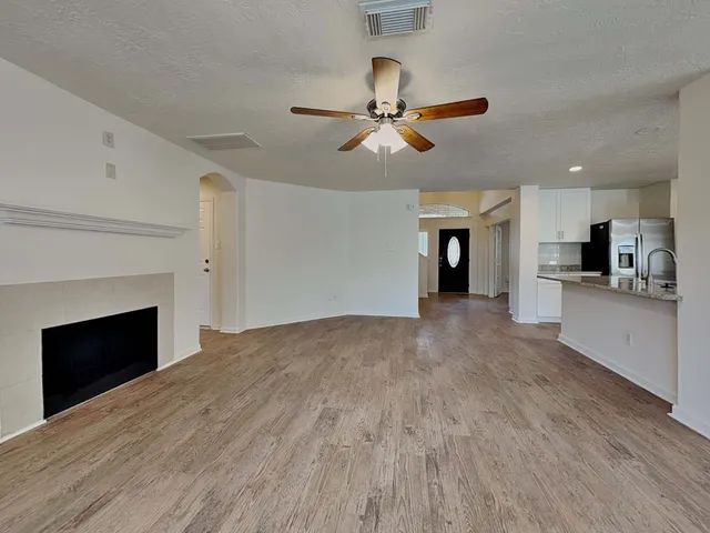 an empty room with wooden floor fan and windows