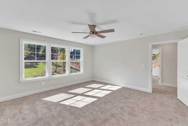 an empty room with wooden floor ceiling fan and windows