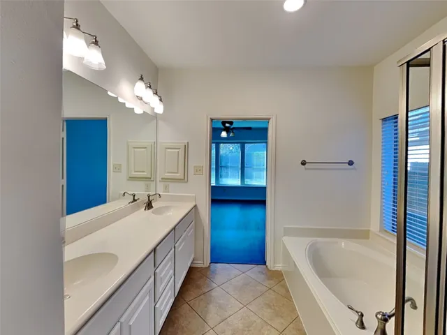 a bathroom with a double vanity sink a mirror a bathtub and shower