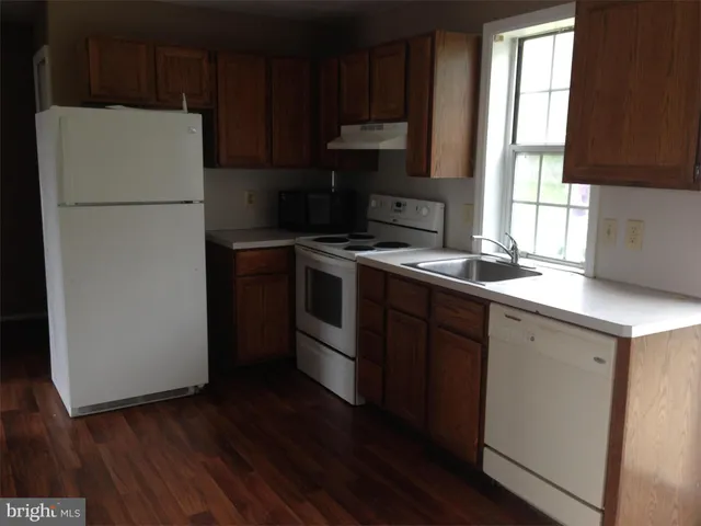 a kitchen with a refrigerator stove and sink with wooden floor