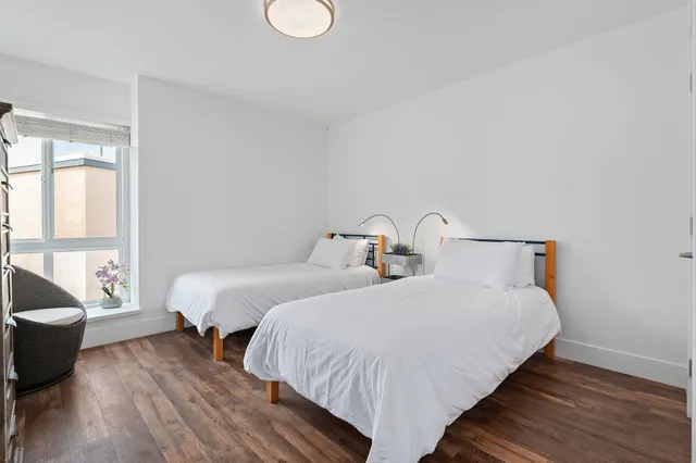 a bedroom with two beds and wooden floor