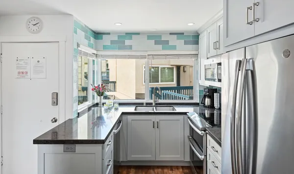 a kitchen with stainless steel appliances granite countertop a refrigerator a sink a stove and a refrigerator