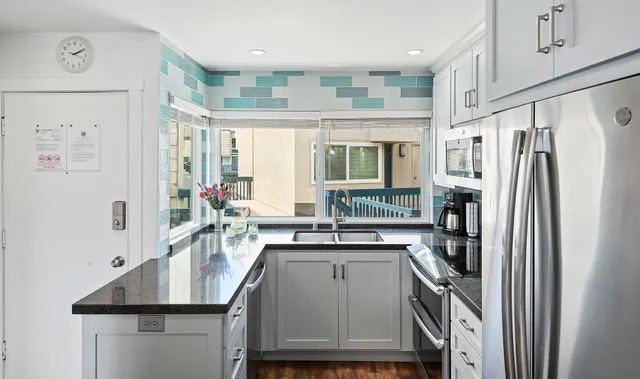 a kitchen with stainless steel appliances granite countertop a refrigerator a sink a stove and a refrigerator