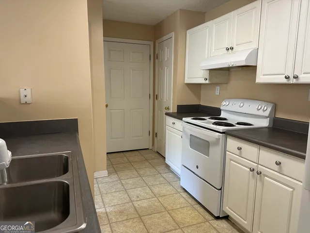a kitchen with granite countertop white cabinets and white appliances