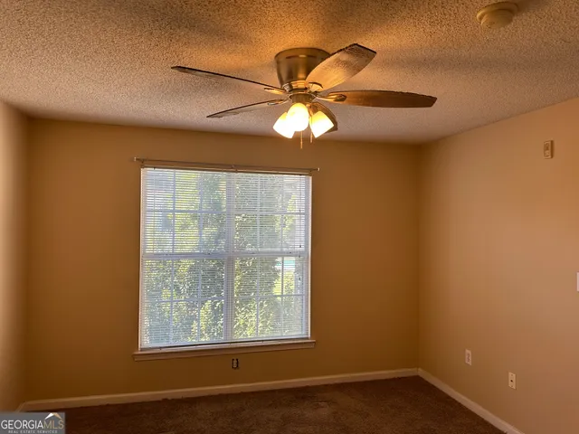 an empty room with windows and fan