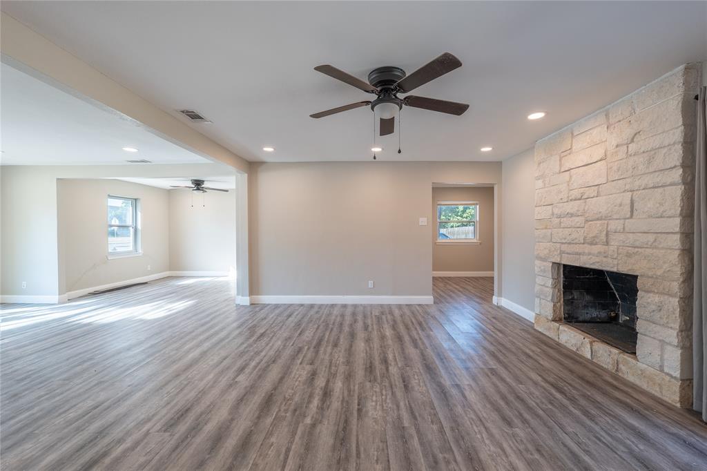 11005 Ferguson Road Dallas, TX 75228 - Photo 7 of 23 Spacious living area featuring wood-finish flooring, recessed lighting, and a stone-clad fireplace