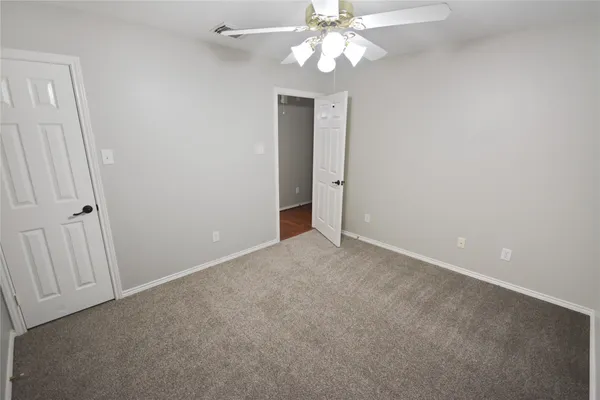 an empty room with a chandelier fan and closet area