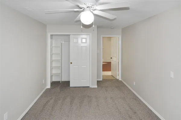 an empty room with closet and a ceiling fan