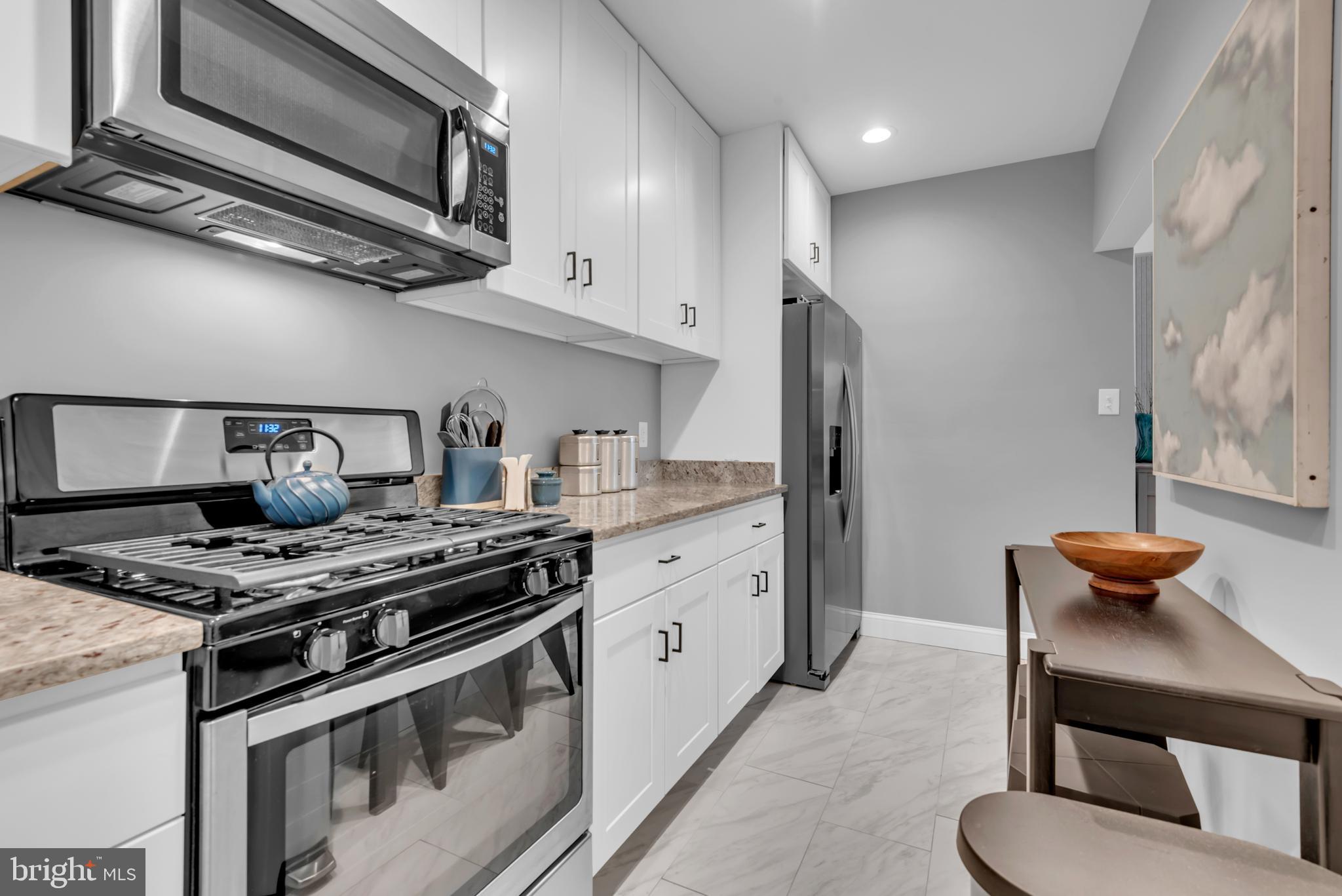 3020 Porter Street Northwest, Unit 103 Washington, DC 20008 - Photo 18 of 30 a kitchen with stainless steel appliances granite countertop a stove and a microwave