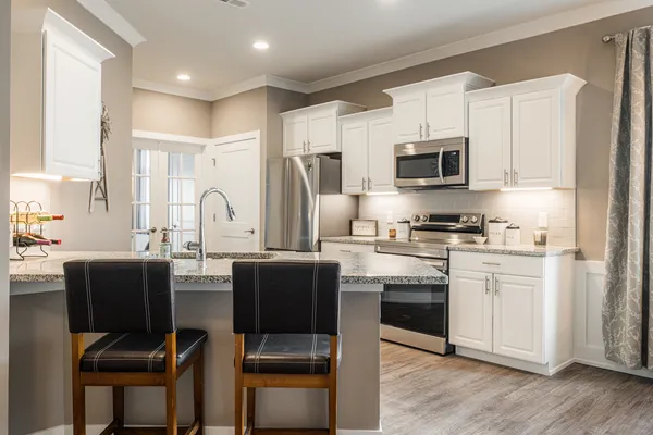 a kitchen with stainless steel appliances a stove a sink refrigerator and a dining table with wooden floor