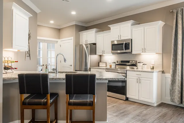 a kitchen with stainless steel appliances a stove a sink refrigerator and a dining table with wooden floor