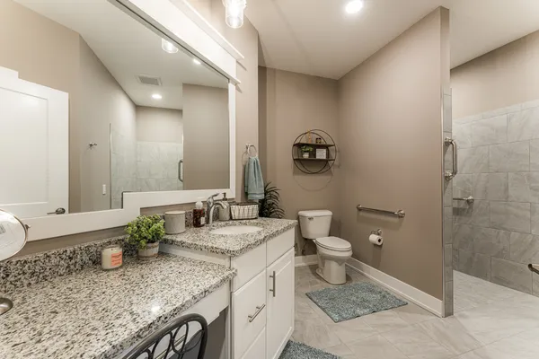 a spacious bathroom with a granite countertop sink toilet and shower