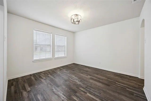 an empty room with wooden floor and mirror