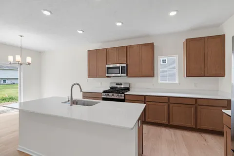 a kitchen with stainless steel appliances a sink a stove a microwave a refrigerator a sink and cabinets