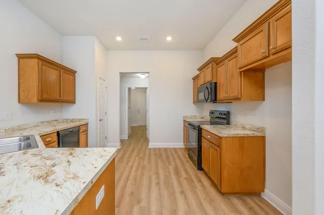 a kitchen with stainless steel appliances granite countertop a sink stove and wooden cabinets