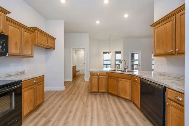 a large kitchen with stainless steel appliances granite countertop a sink dishwasher stove and wooden cabinets