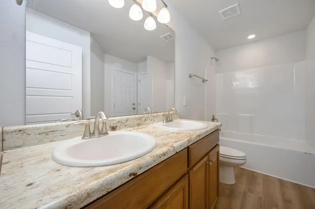 a bathroom with a granite countertop sink a toilet a mirror and shower
