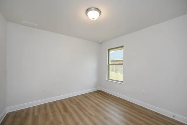 an empty room with a window and wooden floor
