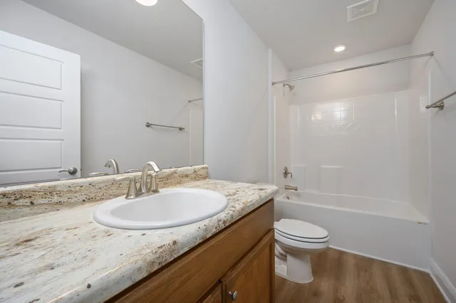 a bathroom with a granite countertop sink toilet and shower