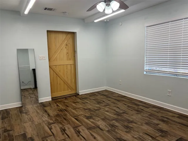 an empty room with wooden floor cabinet and windows