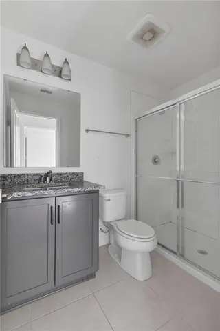a bathroom with a granite countertop sink a toilet and a mirror