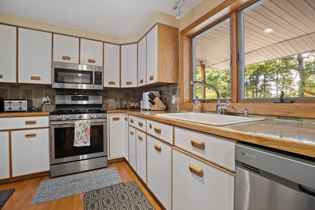 19 Manor Avenue Natick, MA 01760 - Photo 8 of 29 a kitchen with stainless steel appliances granite countertop a sink a stove and a microwave